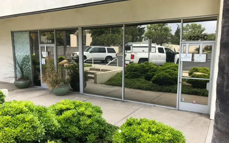 Storefront glazing carrying mirrored solar film under overcast light.